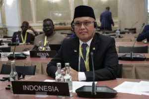 Foto profil Wakil Ketua Komisi I DPR RI Sukamta dengan latar belakang bendera Merah Putih di gedung parlemen.
