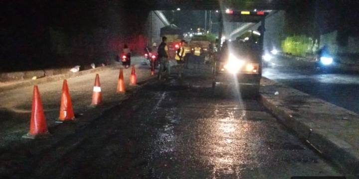 Petugas Dinas PUPR Kota Tangerang sedang melakukan pengaspalan ulang dengan material hotmix di Underpass Ciledug di bawah pencahayaan lampu jalan.