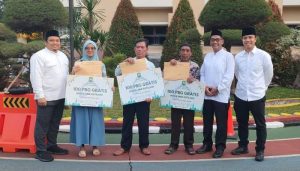 Pejabat Pemkot Tangerang sedang menyerahkan dokumen sertifikat PBG gratis kepada perwakilan warga berpenghasilan rendah di depan rumah yang baru direnovasi.