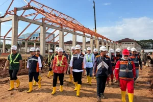 Perspektif digital maket arsitektur modern bangunan Sekolah Rakyat yang sedang dalam tahap konstruksi struktural oleh pekerja PT Nindya Karya (Persero) di salah satu wilayah terpencil Indonesia.