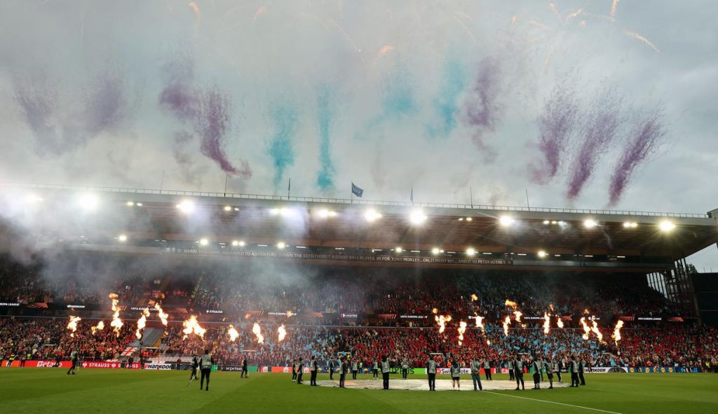 Foto para pemain Aston Villa mengangkat trofi juara Liga Europa di atas podium dengan konfeti yang meriah di Tupras Stadium.