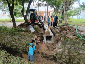Pekerja dari Dinas PUPR Kota Tangerang sedang melakukan pemasangan beton saluran drainase silang di kawasan Grand Duta Periuk.