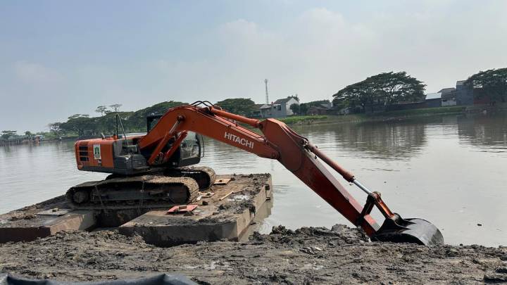 Alat berat ekskavator sedang mengeruk lumpur dan sedimentasi di Situ Bulakan Tangerang untuk memperluas daya tampung air.