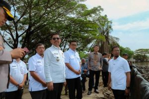 Alat berat ekskavator sedang melakukan pengerukan lumpur sedimentasi di pinggir Situ Bulakan dipantau oleh jajaran pejabat daerah.