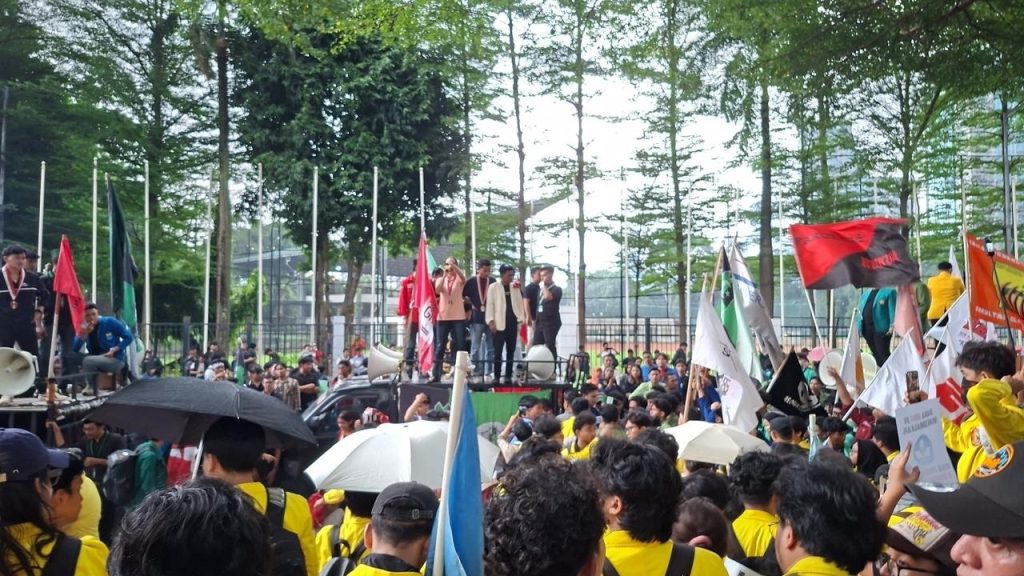 Massa mahasiswa BEM UI mengenakan jaket kuning berkumpul memadati jalan protokol Jakarta membawa spanduk tuntutan.