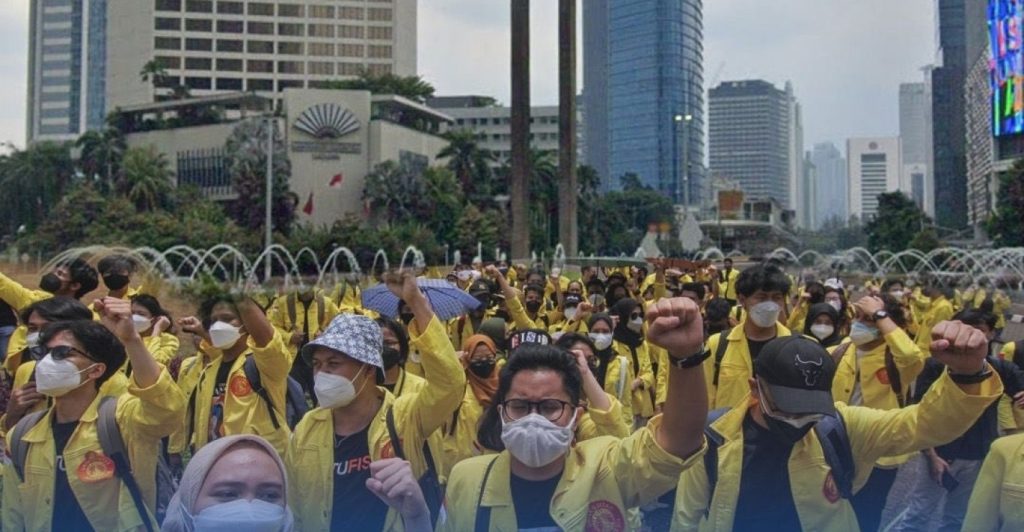 Petugas kepolisian mengamankan barang bukti botol kaca berisi sumbu bom molotov, berlatar belakang barikade polisi di dekat Halte Tosari Jakarta saat malam hari.