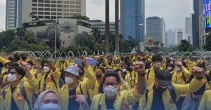 Petugas kepolisian mengamankan barang bukti botol kaca berisi sumbu bom molotov, berlatar belakang barikade polisi di dekat Halte Tosari Jakarta saat malam hari.