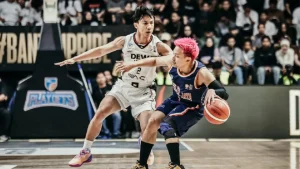 Andakara Prastawa melakukan manuver lay-up melewati penjagaan ketat Joshua Ibarra di dalam area paint Dewa United Arena.