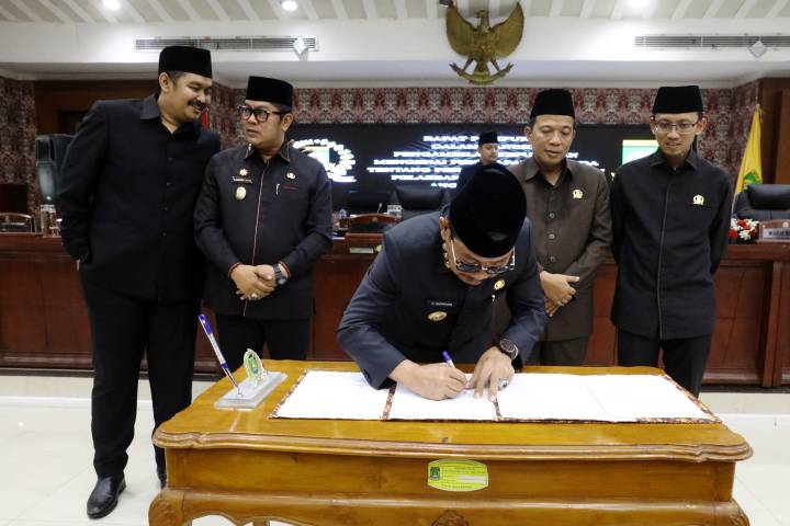 Foto horizontal memperlihatkan Wali Kota Tangerang H. Sachrudin bersama Wakil Wali Kota H. Maryono dan jajaran pimpinan DPRD Kota Tangerang memegang dokumen Perda APBD 2025 yang baru saja ditandatangani.