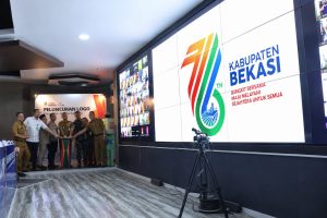 Tampilan grafis interaktif logo angka 76 bernuansa modern yang diproyeksikan pada layar digital utama ruang kendali darurat Pemerintah Kabupaten Bekasi.