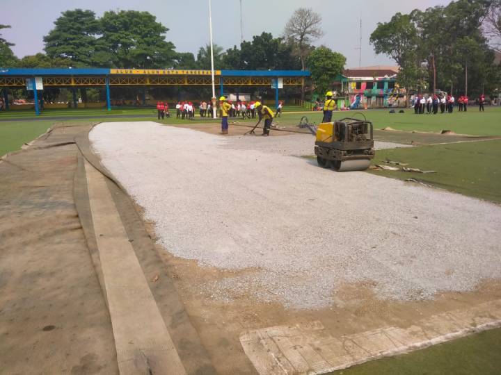 Petugas Dinas PUPR Kota Tangerang melakukan pengurukan dan perataan pasir fondasi di area rumput sintetis Lapangan Ahmad Yani.