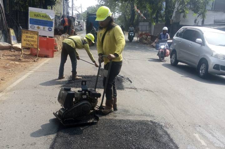 Petugas Dinas PUPR Kota Tangerang saat melakukan pengaspalan ulang di titik jalan rusak Jatiuwung.