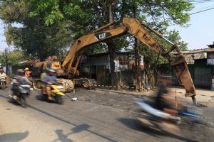 Visualisasi alat berat ekskavator Dinas PUPR Kota Tangerang sedang melakukan pengerukan tanah dan penyiapan struktur dasar sebelum proses pengecoran beton di sepanjang Jalan Iskandar Muda, Neglasari.